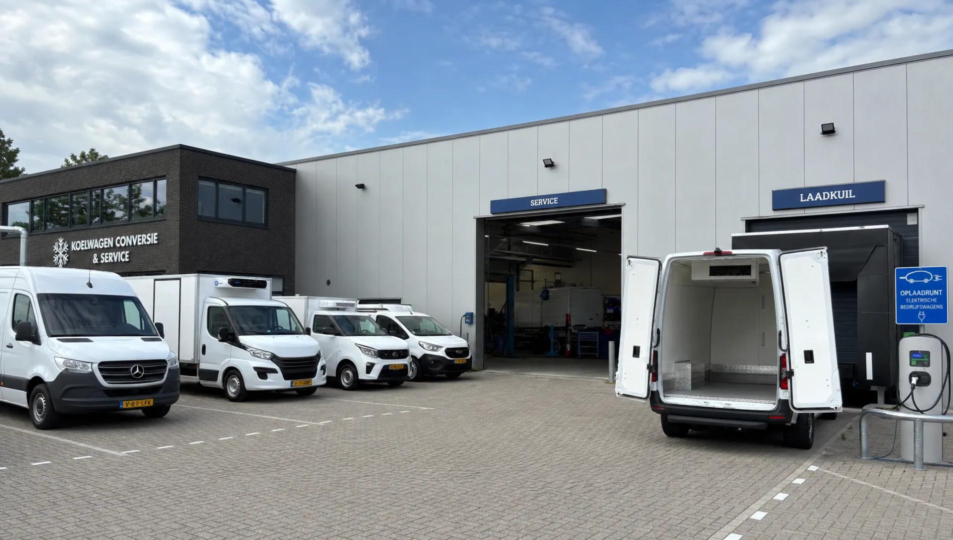 Een industriële voorhof met bedrijfsauto's voor gekoeld transport, een open servicebay en een open laadruimte bij de ombouwlocatie.