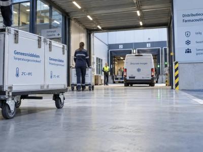 Een gekoelde bestelbus staat bij de overdekte laadzone van een distributiecentrum waar afgesloten farmaceutische zendingen worden overgedragen.