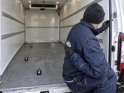 Een technicus plaatst temperatuurloggers op verschillende plekken in de lege laadruimte van een tweedehands koelwagen.